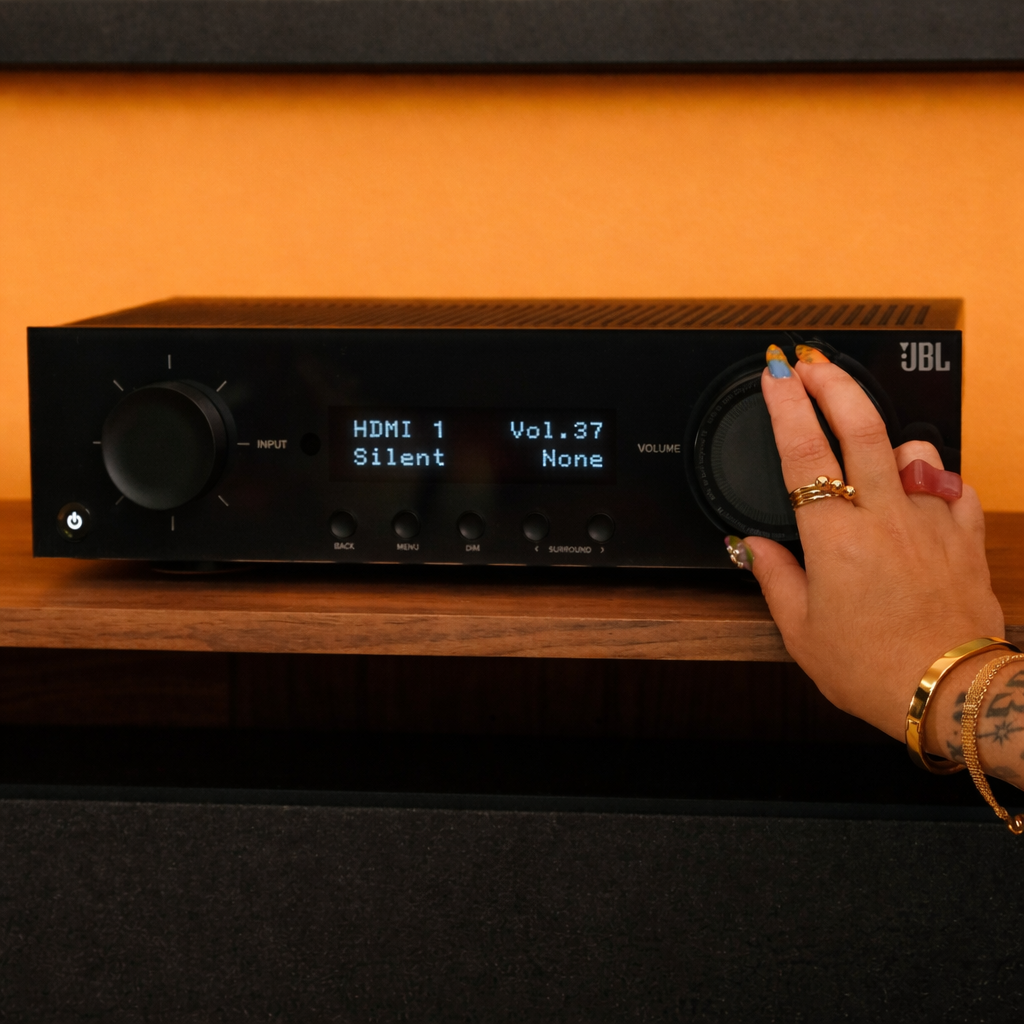 Hand adjusting knobs on a JBL MA510 Net AV Receiver with an orange background
