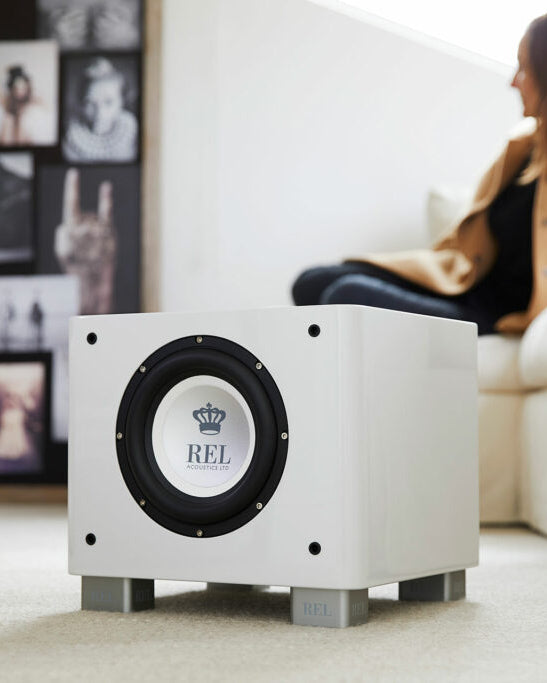 REL Series S White subwoofer with black center in a living room setting.