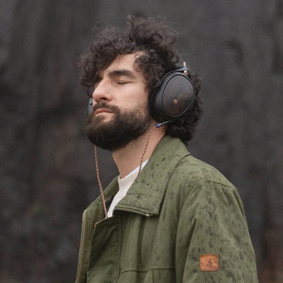 Man wearing Meze Liric headphones with a blurred natural background