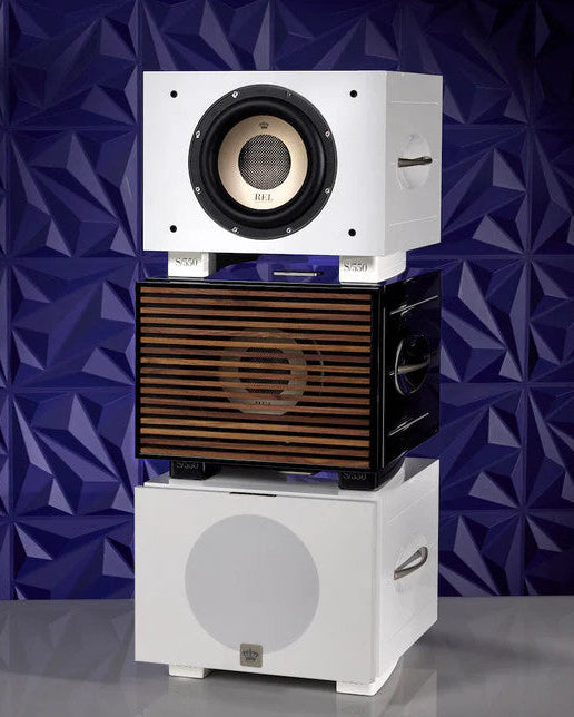 Stack of three REL Series S speakers with a geometric purple background